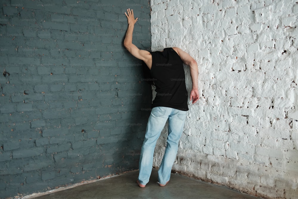 a man leaning against a white brick wall