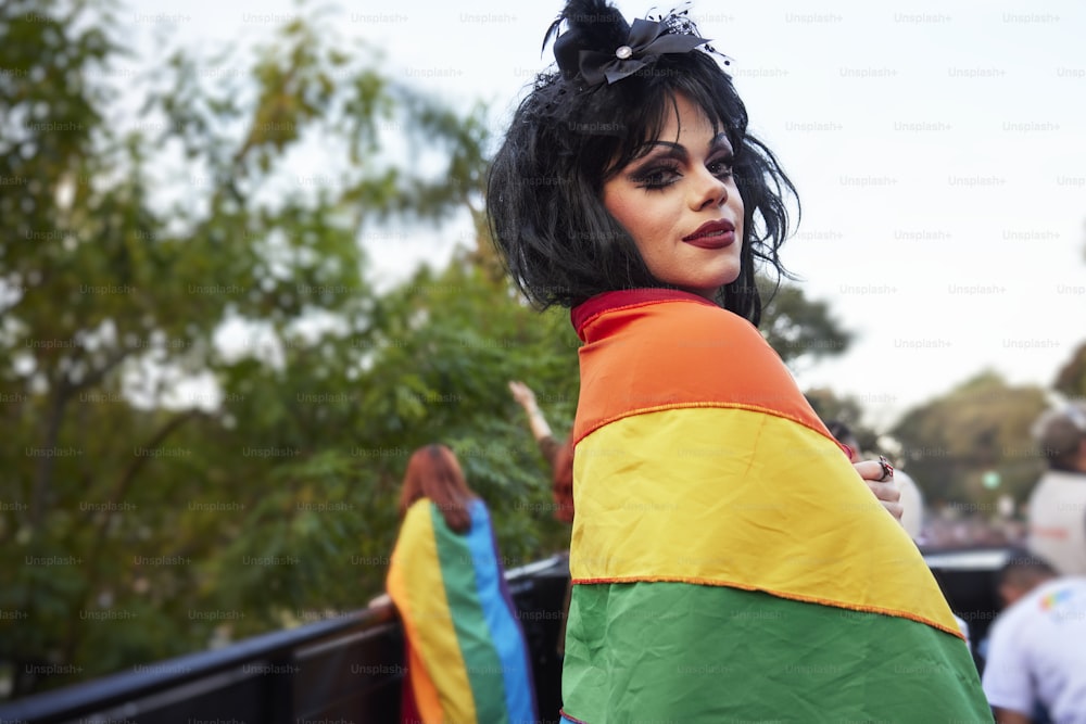 a woman dressed in a colorful outfit standing next to a fence