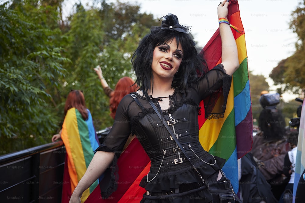 a woman in a black outfit holding a rainbow flag