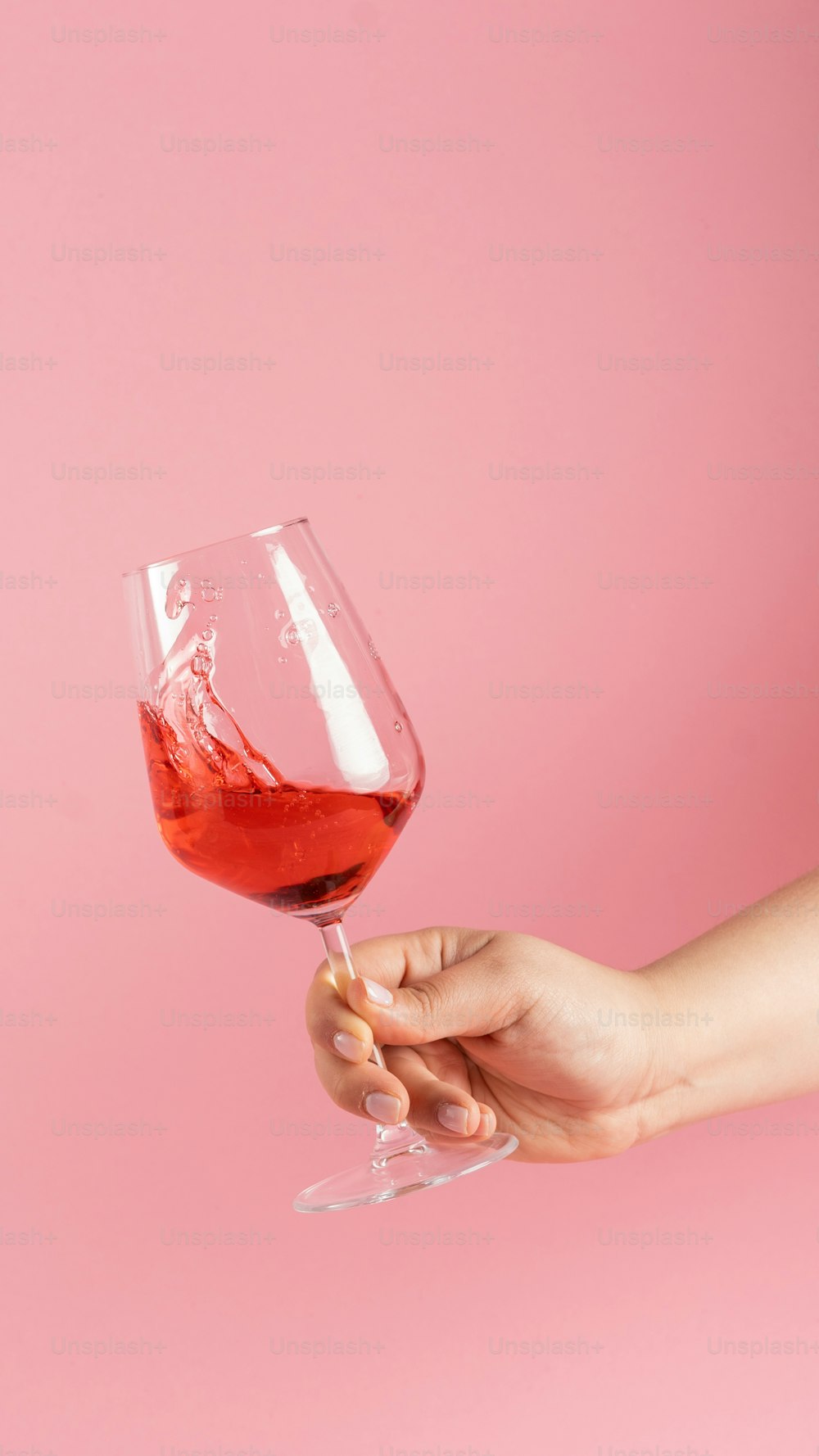 a person holding a wine glass with red wine in it