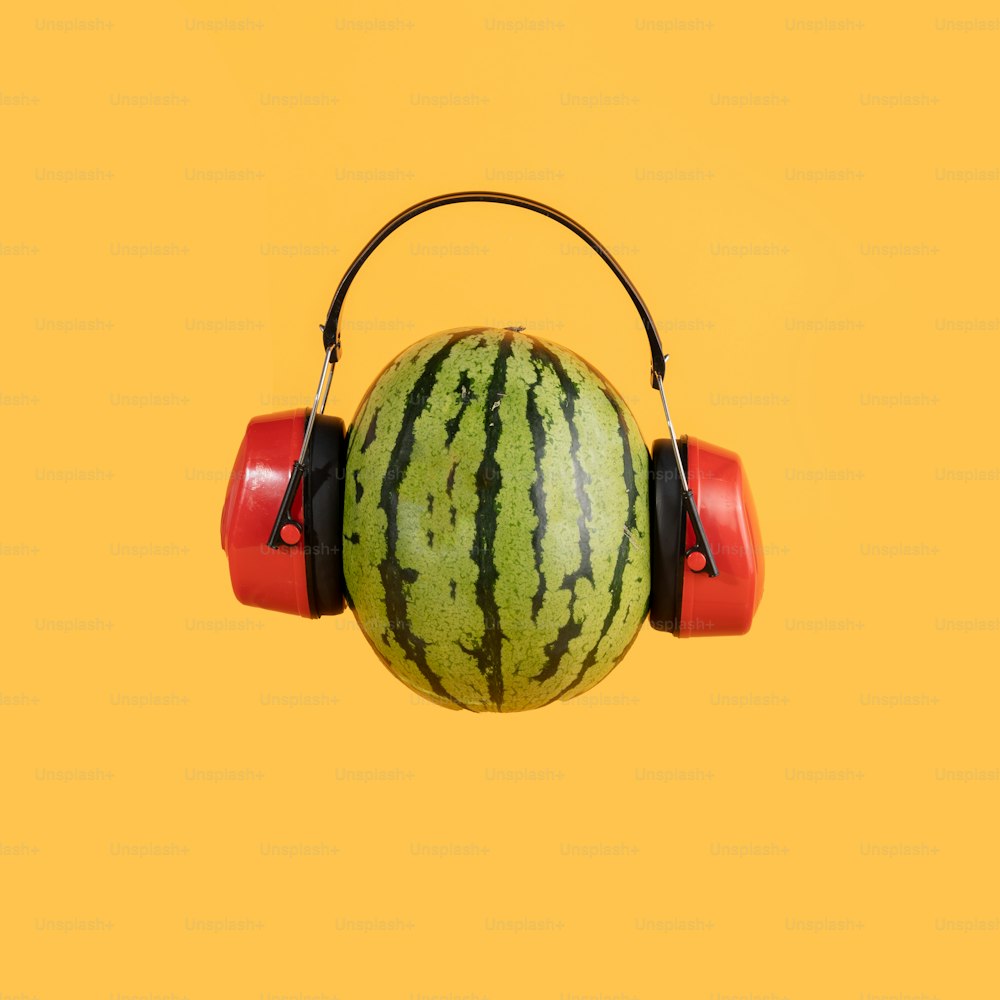 a watermelon with headphones on a yellow background