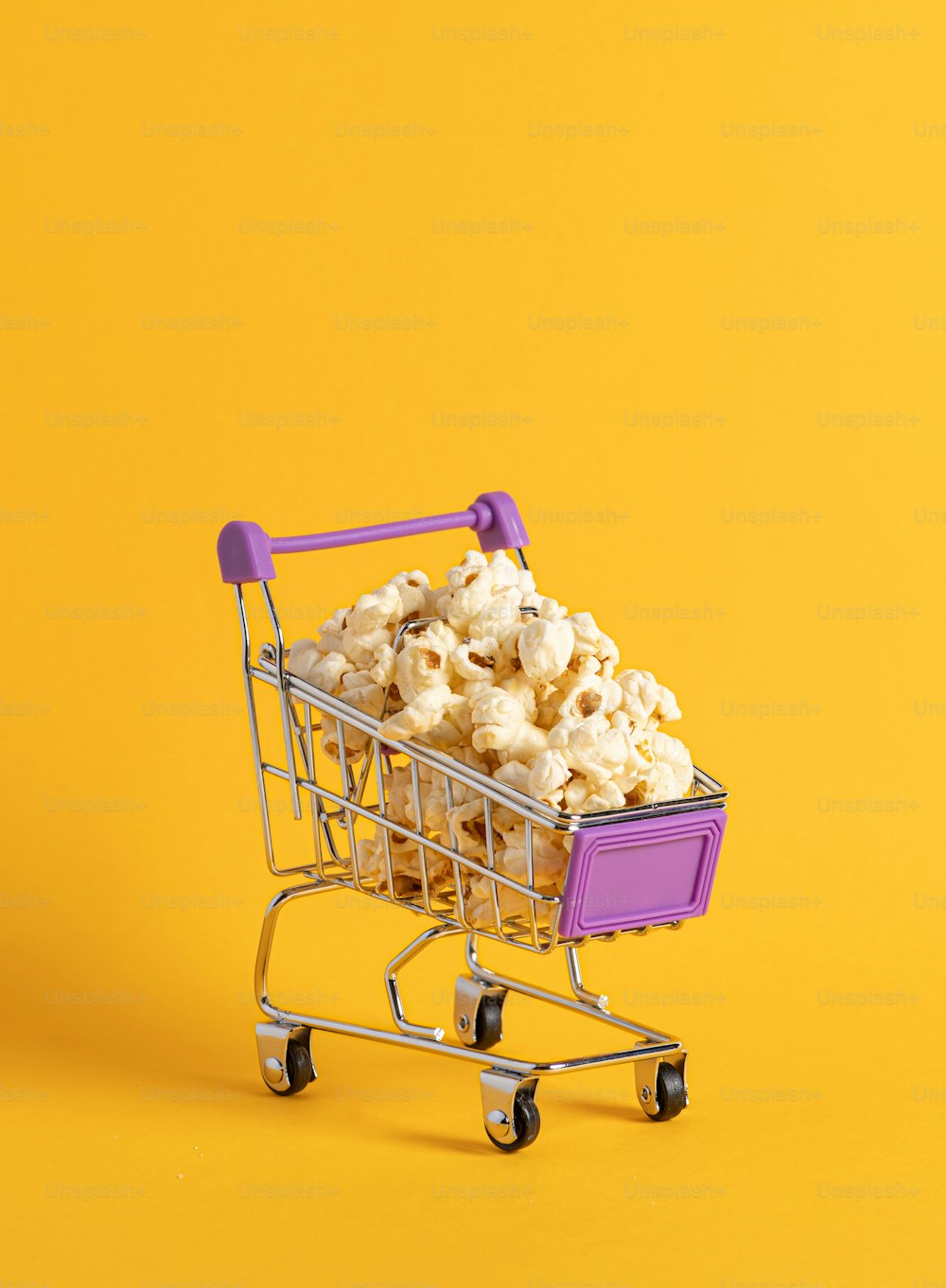 a shopping cart filled with popcorn on a yellow background