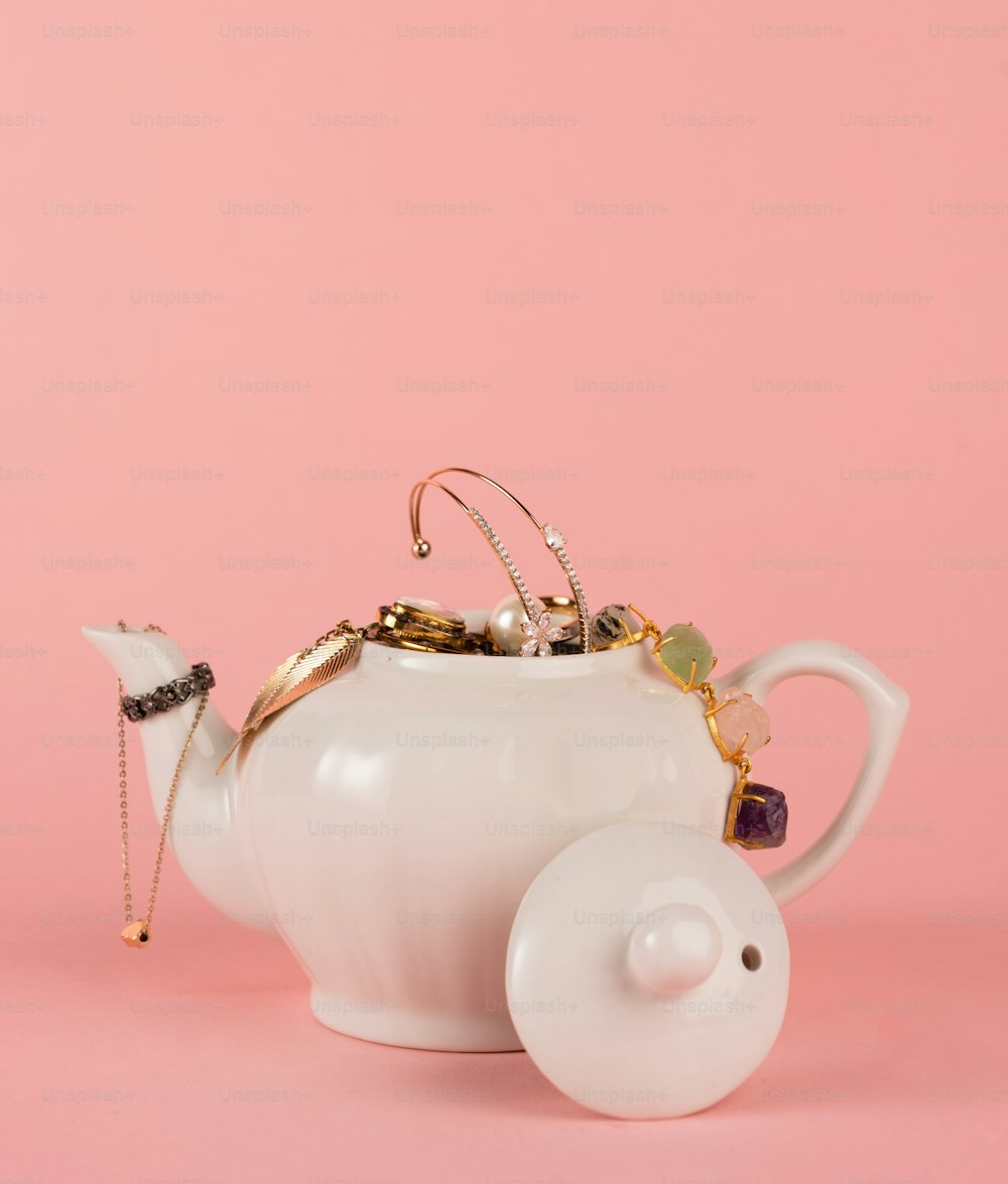 a white teapot with a gold chain on top of it