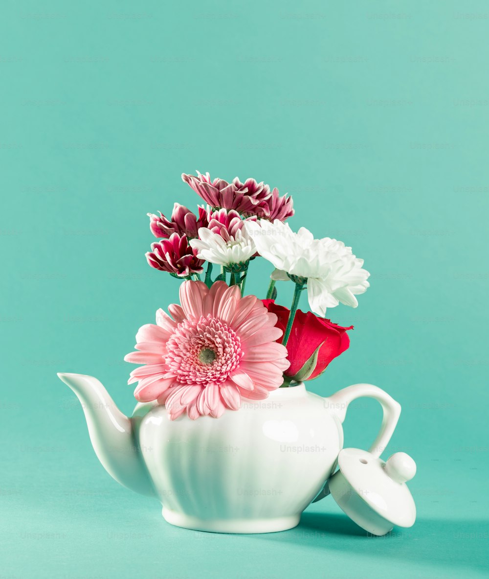 a white teapot with pink and white flowers in it