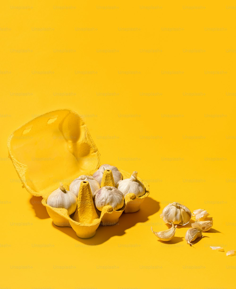 a peeled egg shell next to garlic on a yellow background