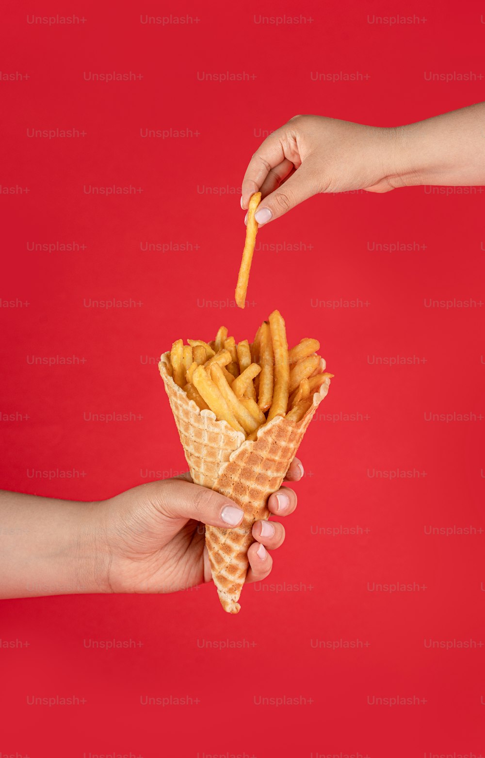 a hand holding a waffle filled with french fries