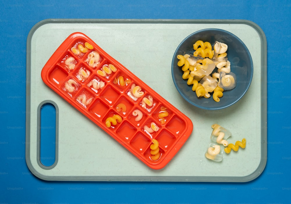 a tray with a bowl of corn and a tray with a bowl of macaro