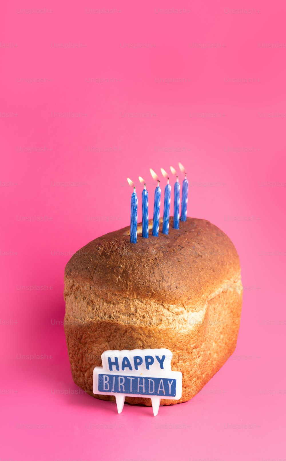 a birthday cake with blue candles on a pink background