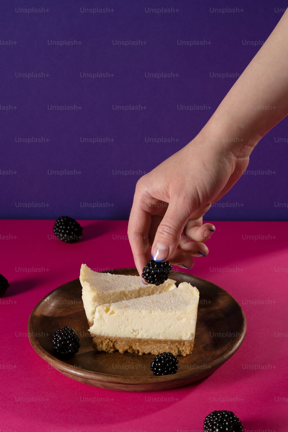 a person reaching for a piece of cheesecake on a plate