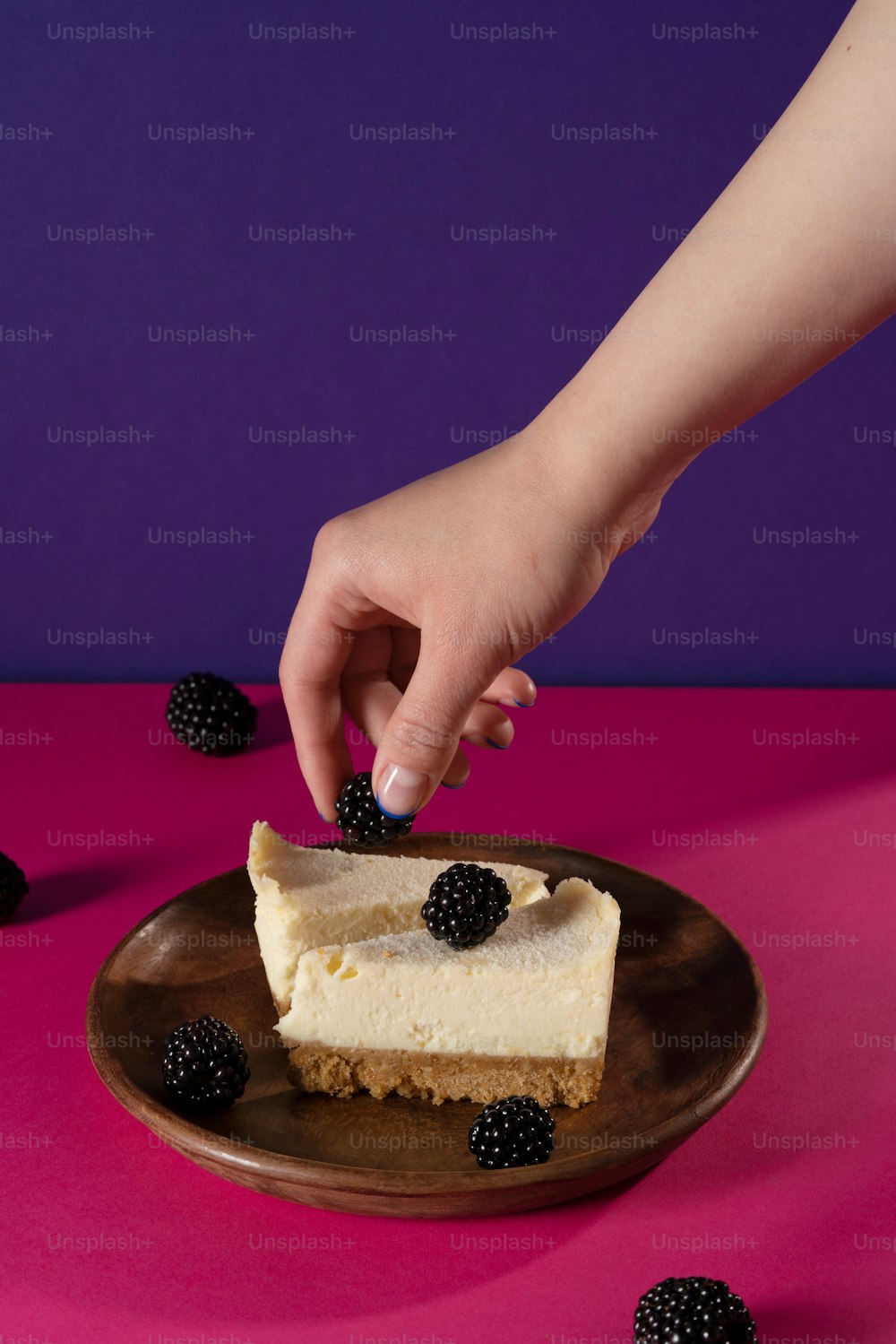 a person reaching for a piece of cheesecake on a plate