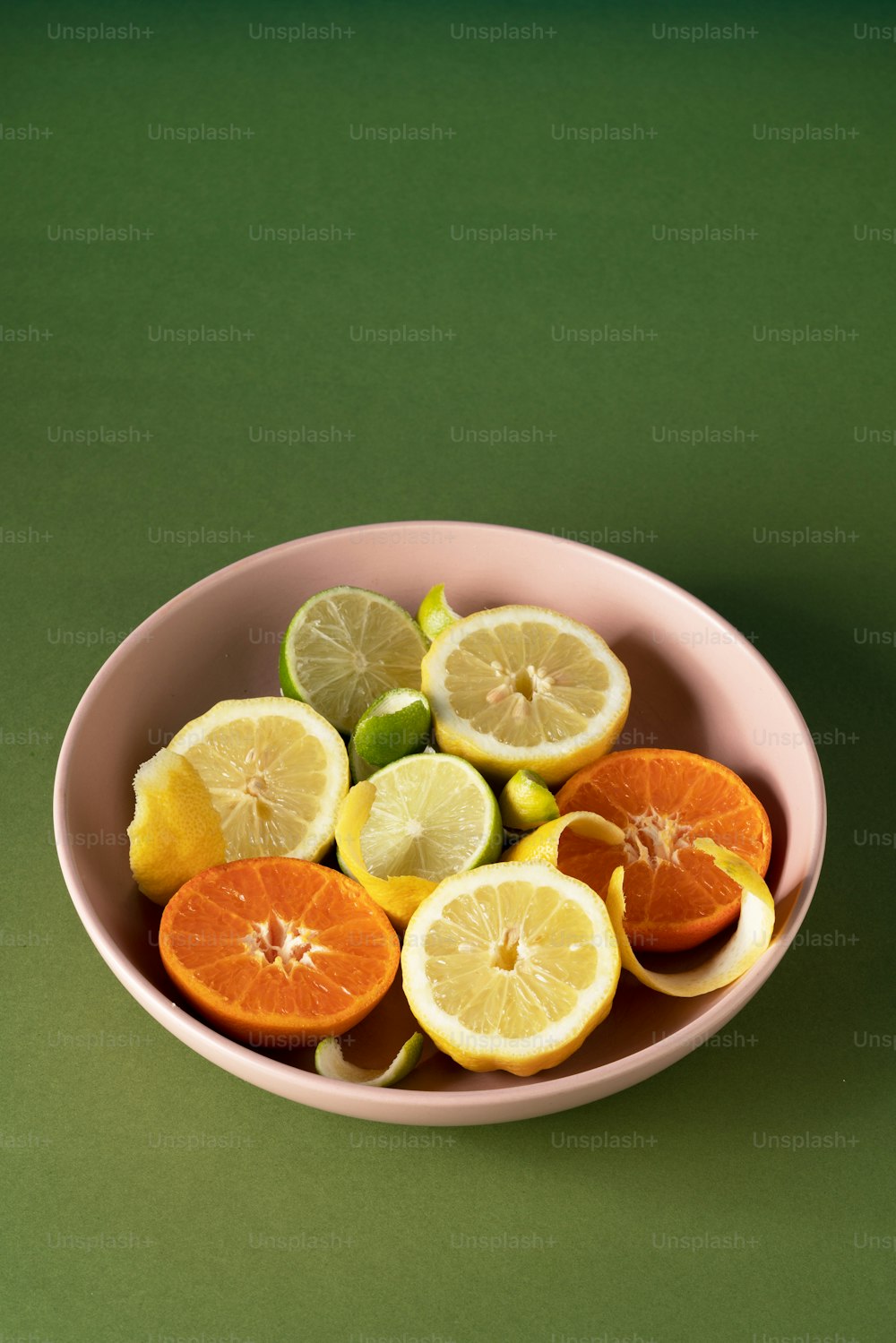 a pink bowl filled with sliced lemons and oranges