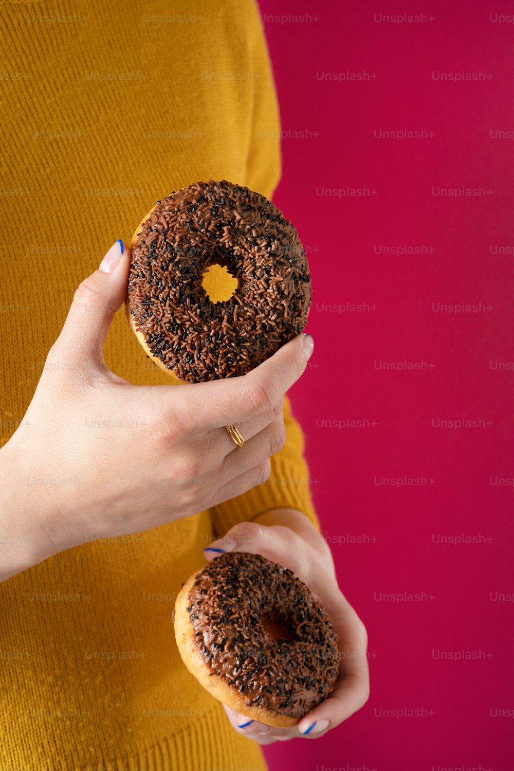 a woman holding a chocolate donut in her hands