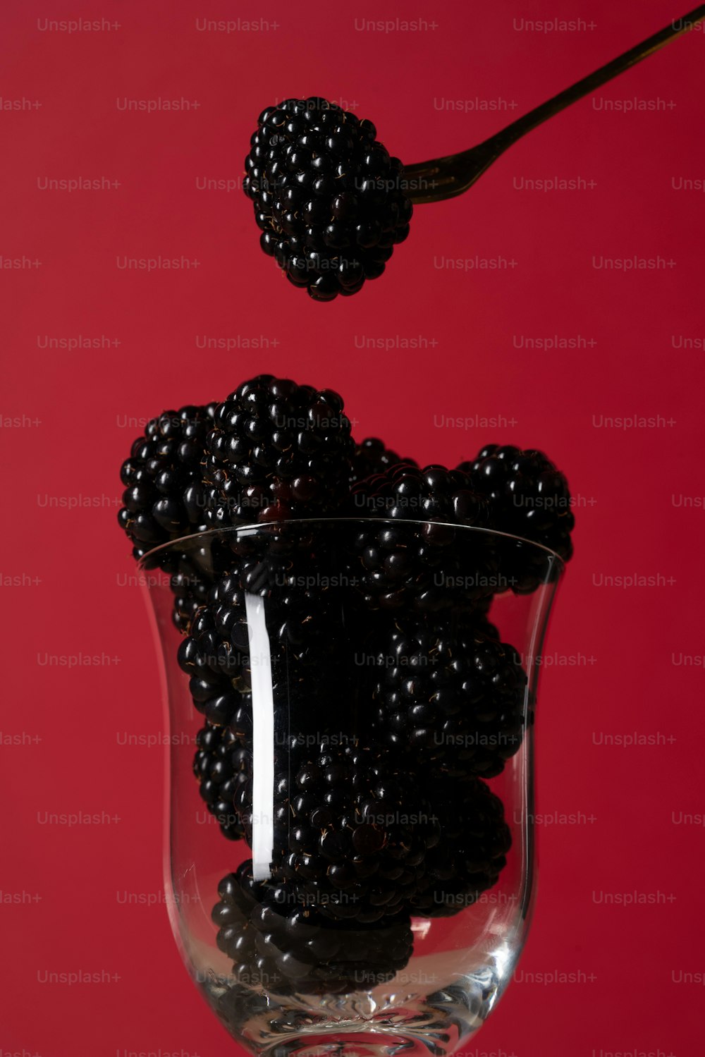 a glass filled with blackberries on top of a table