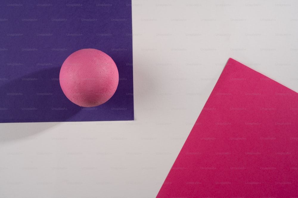 une boule rose posée sur un morceau de papier violet et rose
