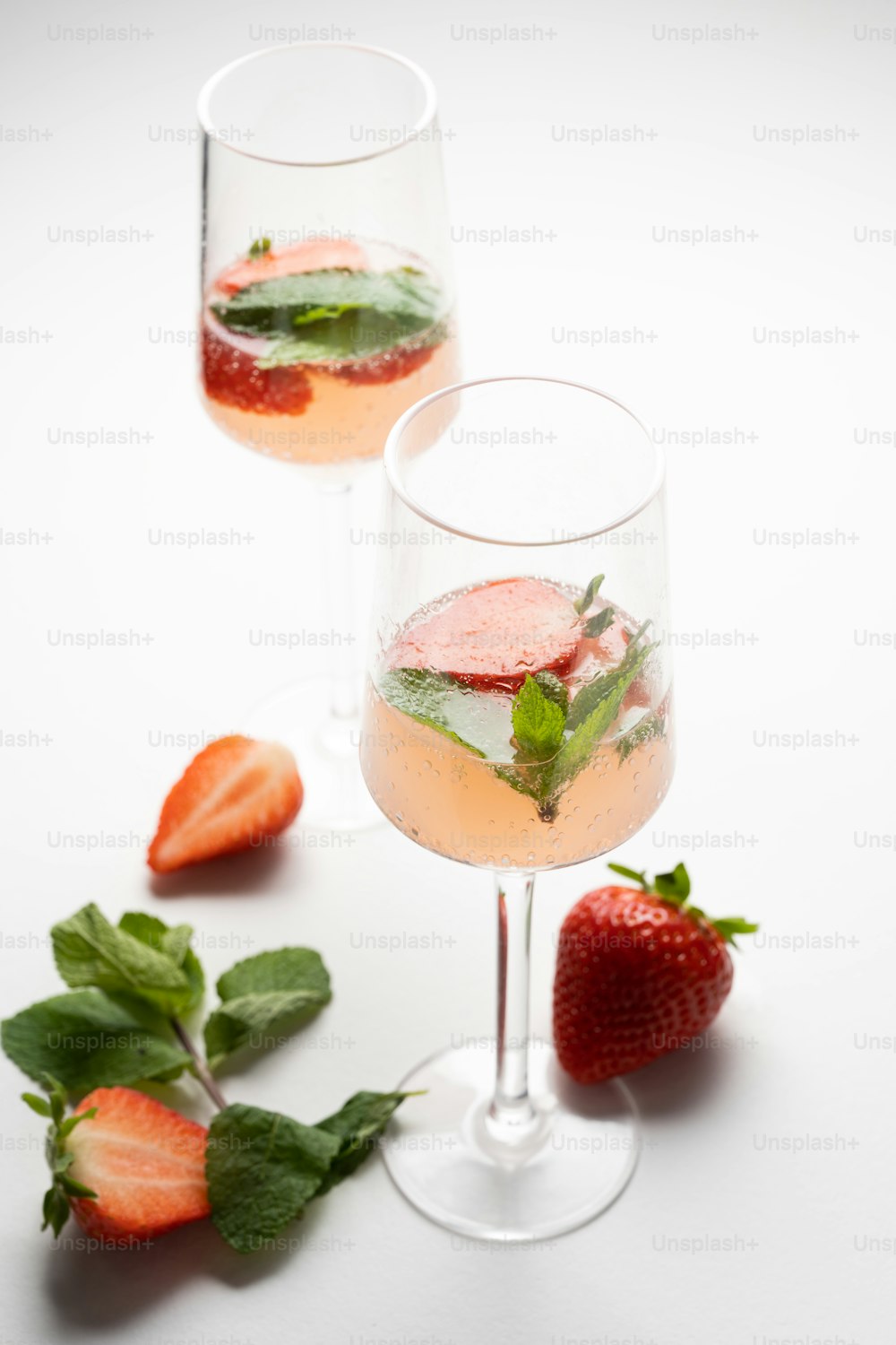 a couple of glasses filled with liquid and strawberries