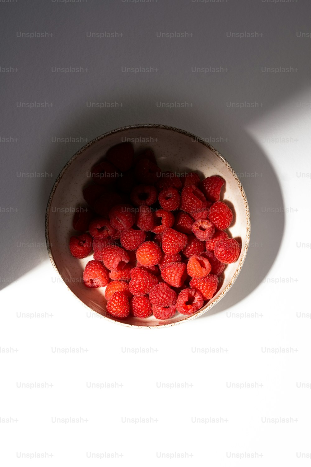 a bowl filled with raspberries on top of a white table