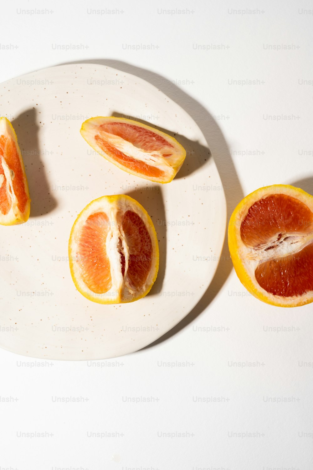 ein weißer Teller mit geschnittenen Orangen auf einem Tisch