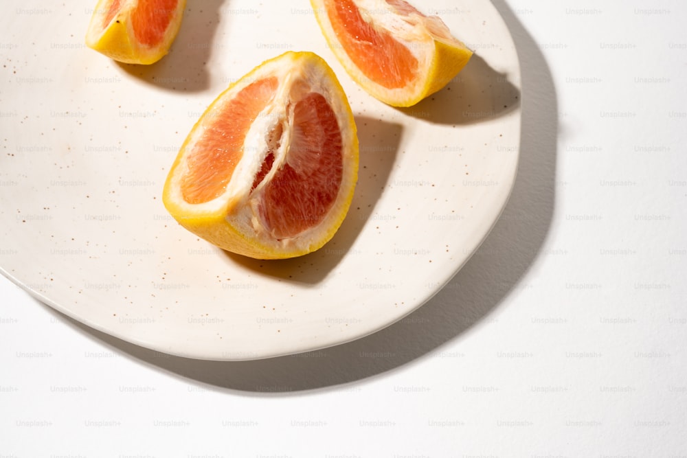 ein weißer Teller mit geschnittenen Orangen auf einem Tisch