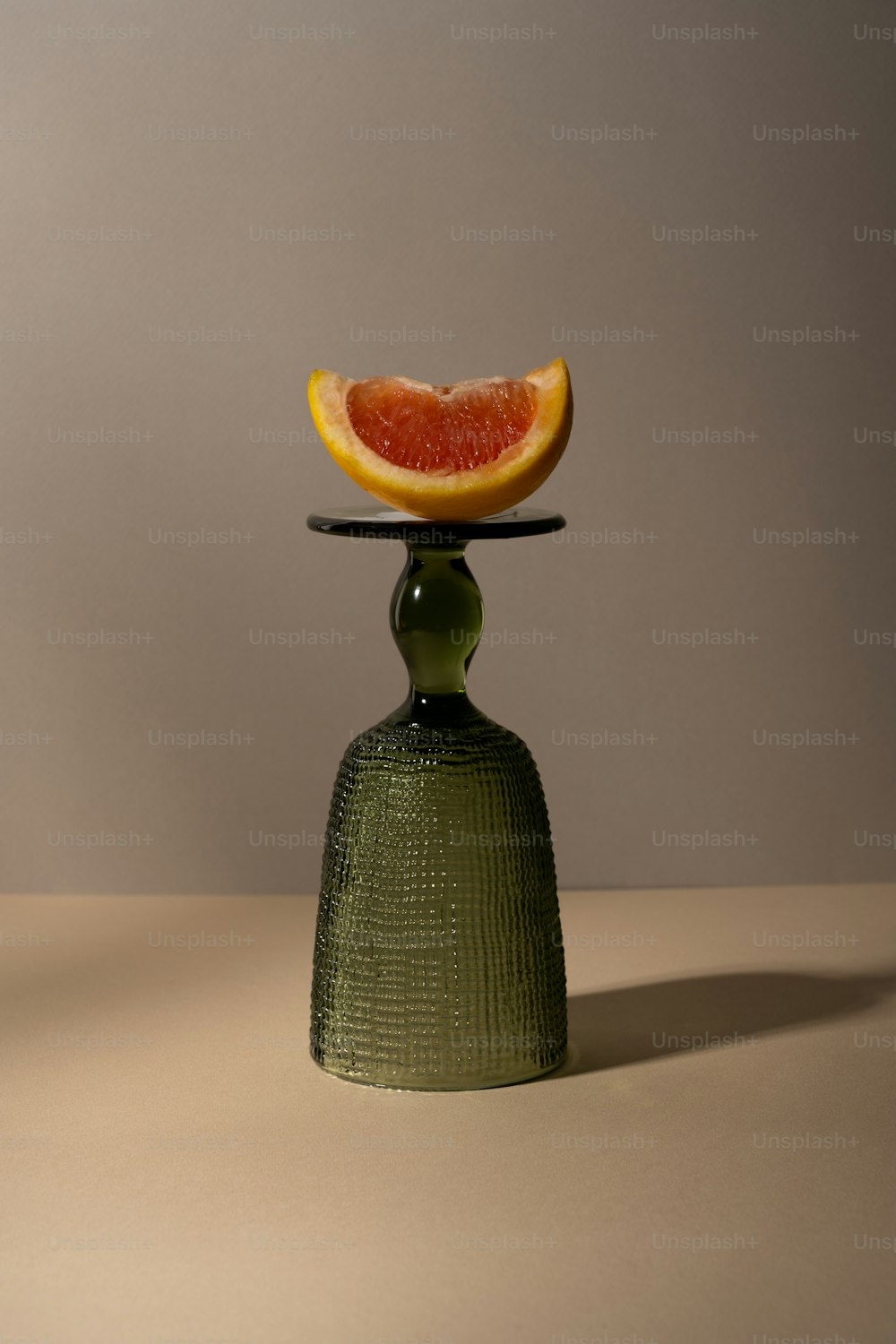 a slice of grapefruit sitting on top of a green vase