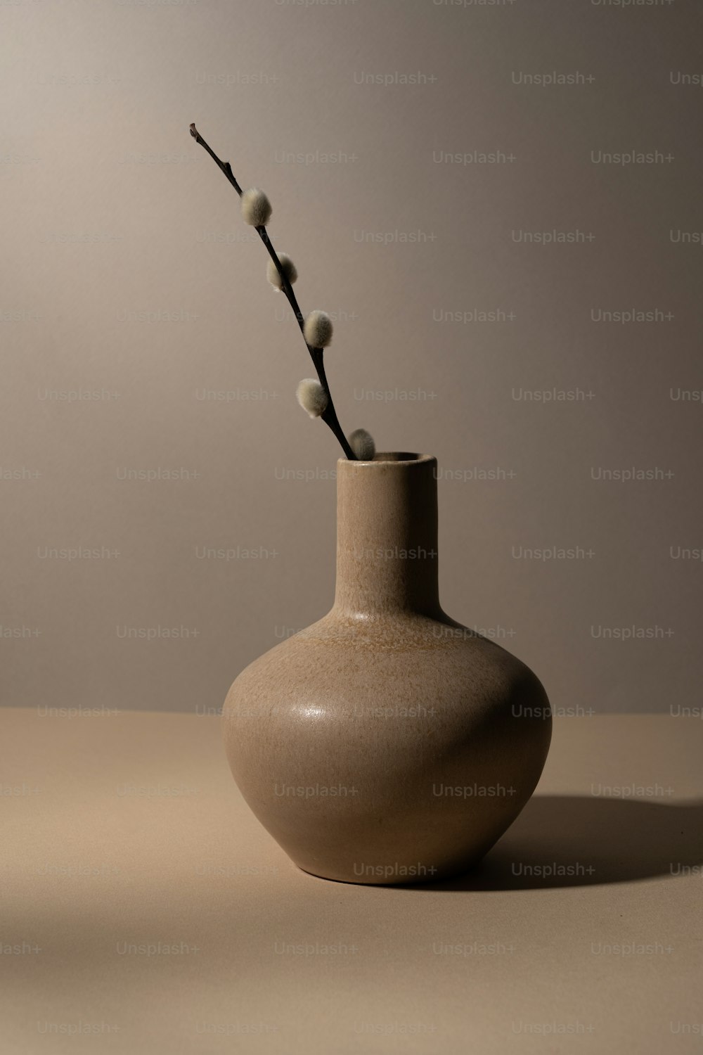 a white vase with a twig sticking out of it