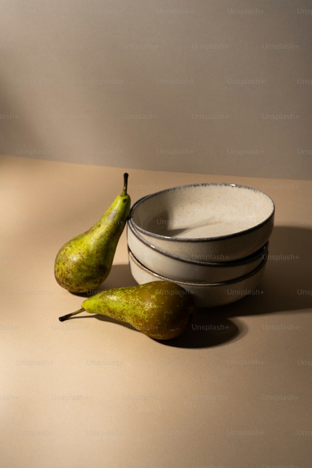 a bowl and two pears on a table