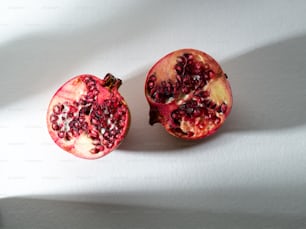 ein Granatapfel, der auf einer weißen Fläche in zwei Hälften geschnitten wird