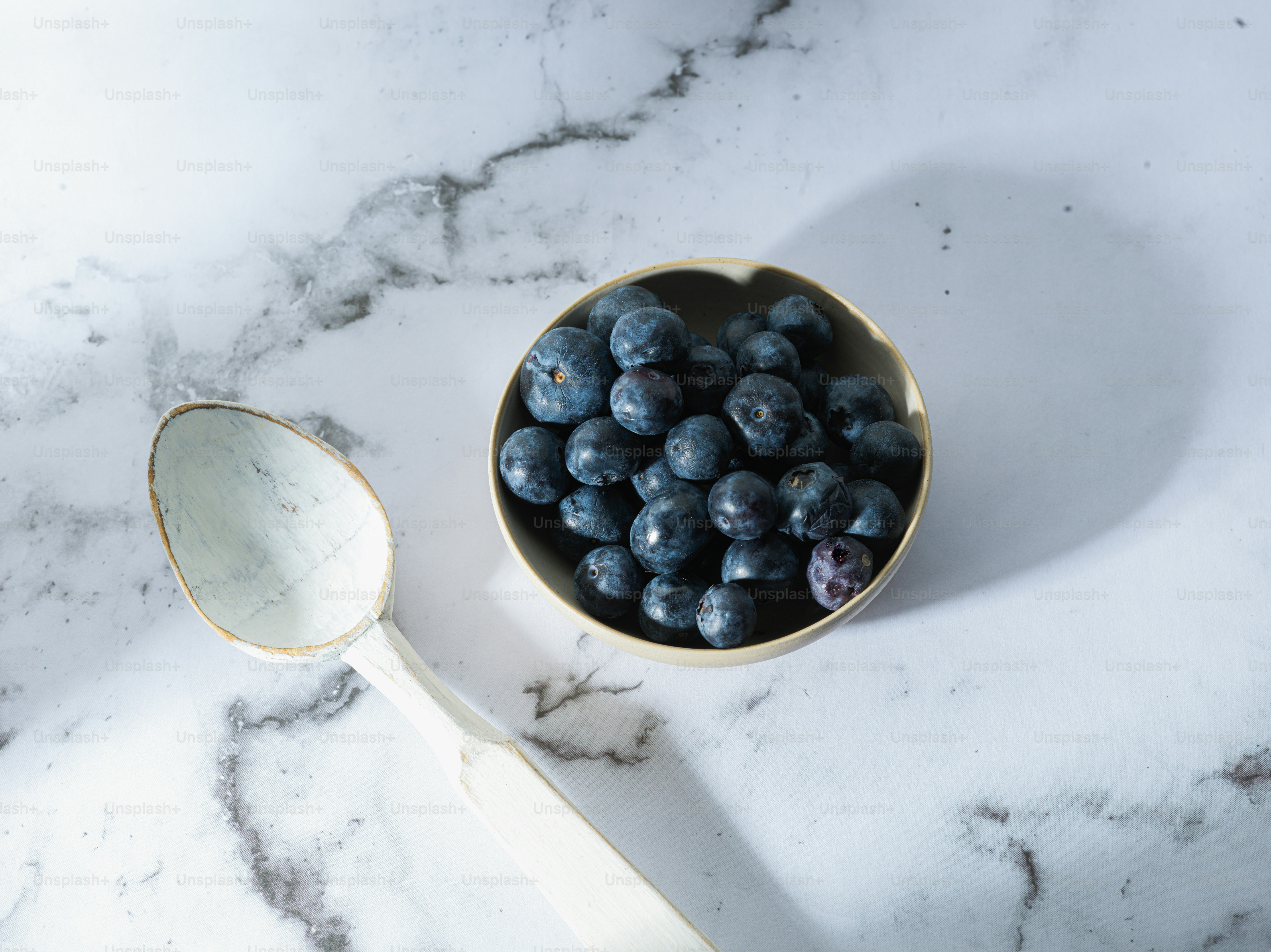 a bowl of blueberries next to a spoon