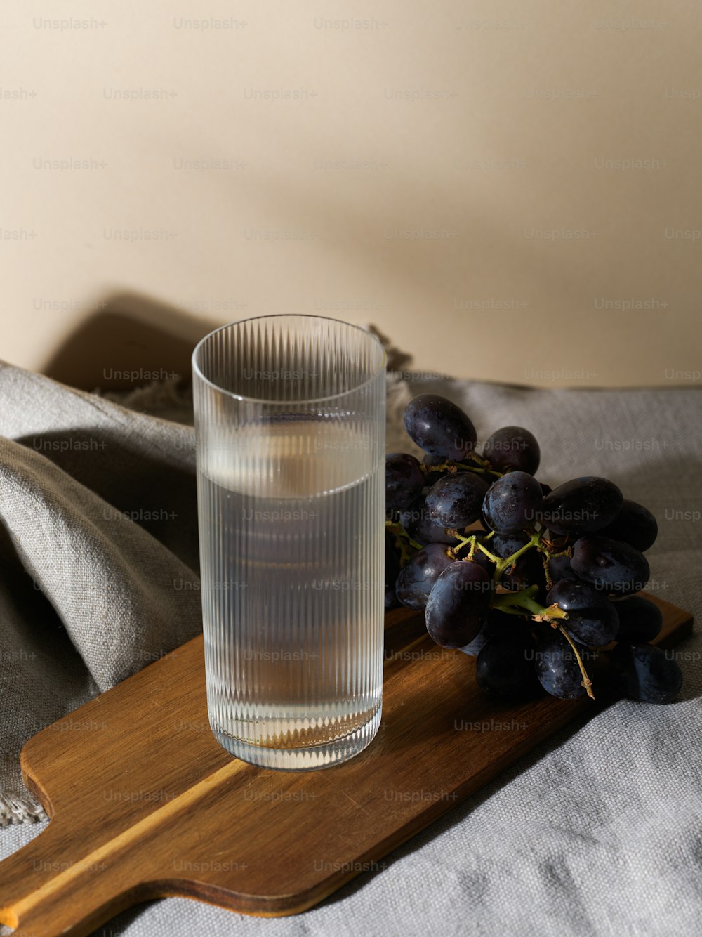 a glass of water next to a bunch of grapes