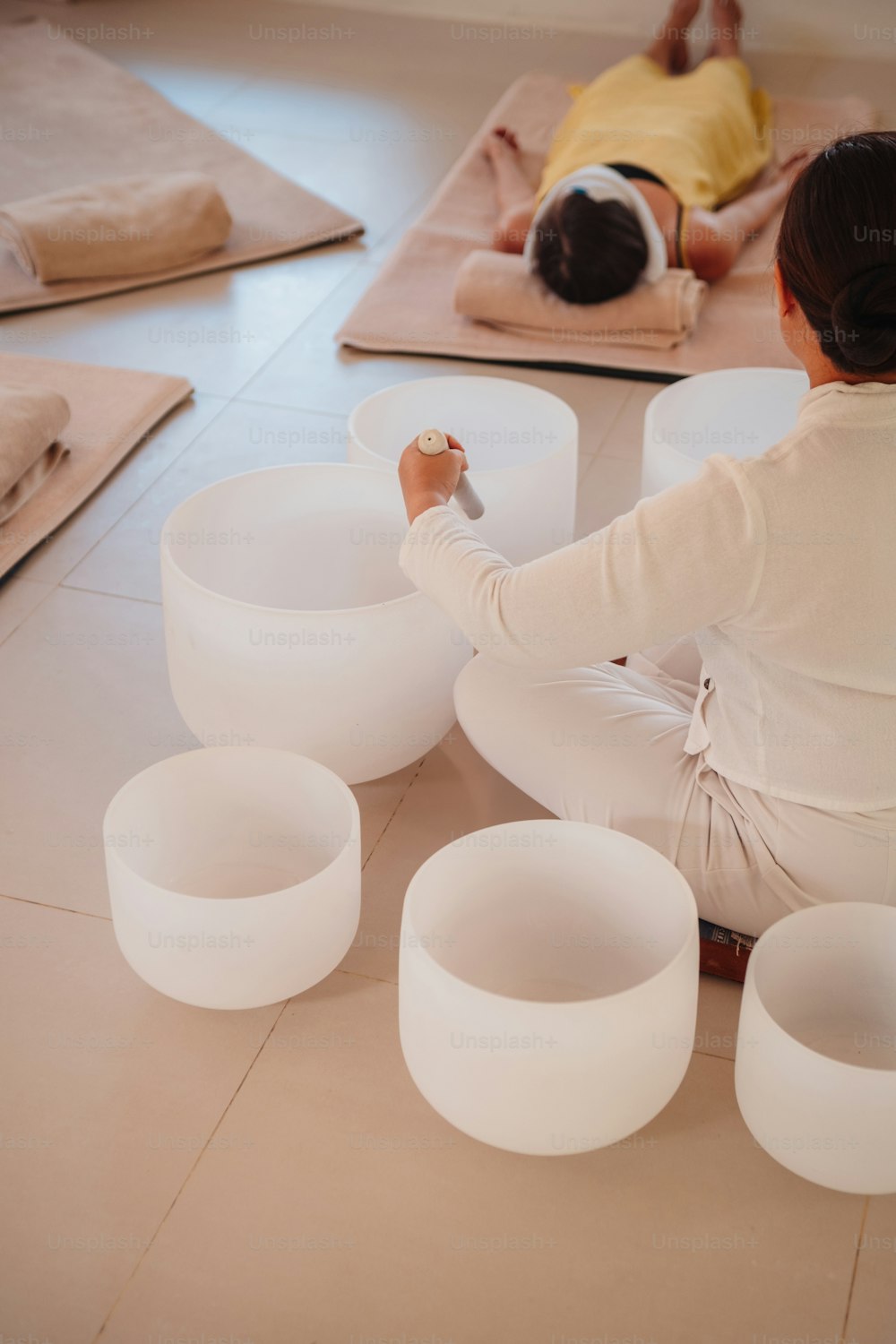 a woman is sitting on the floor with her hands on a bowl
