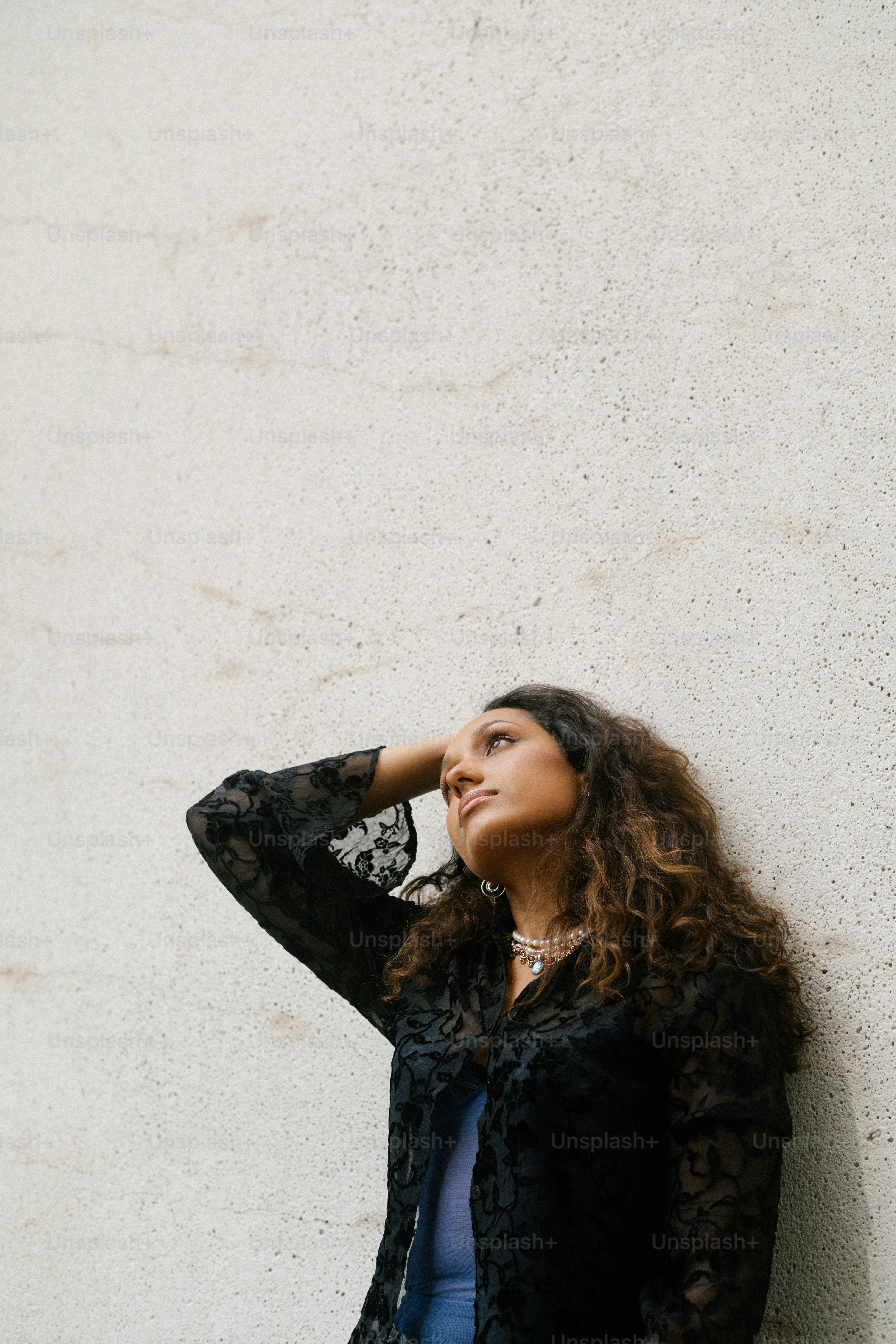 A woman leaning against a wall with her hand on her head photo ...