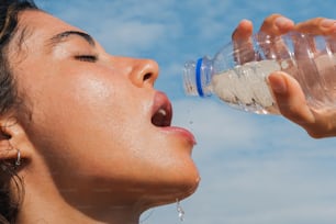 a woman drinking water from a plastic bottle