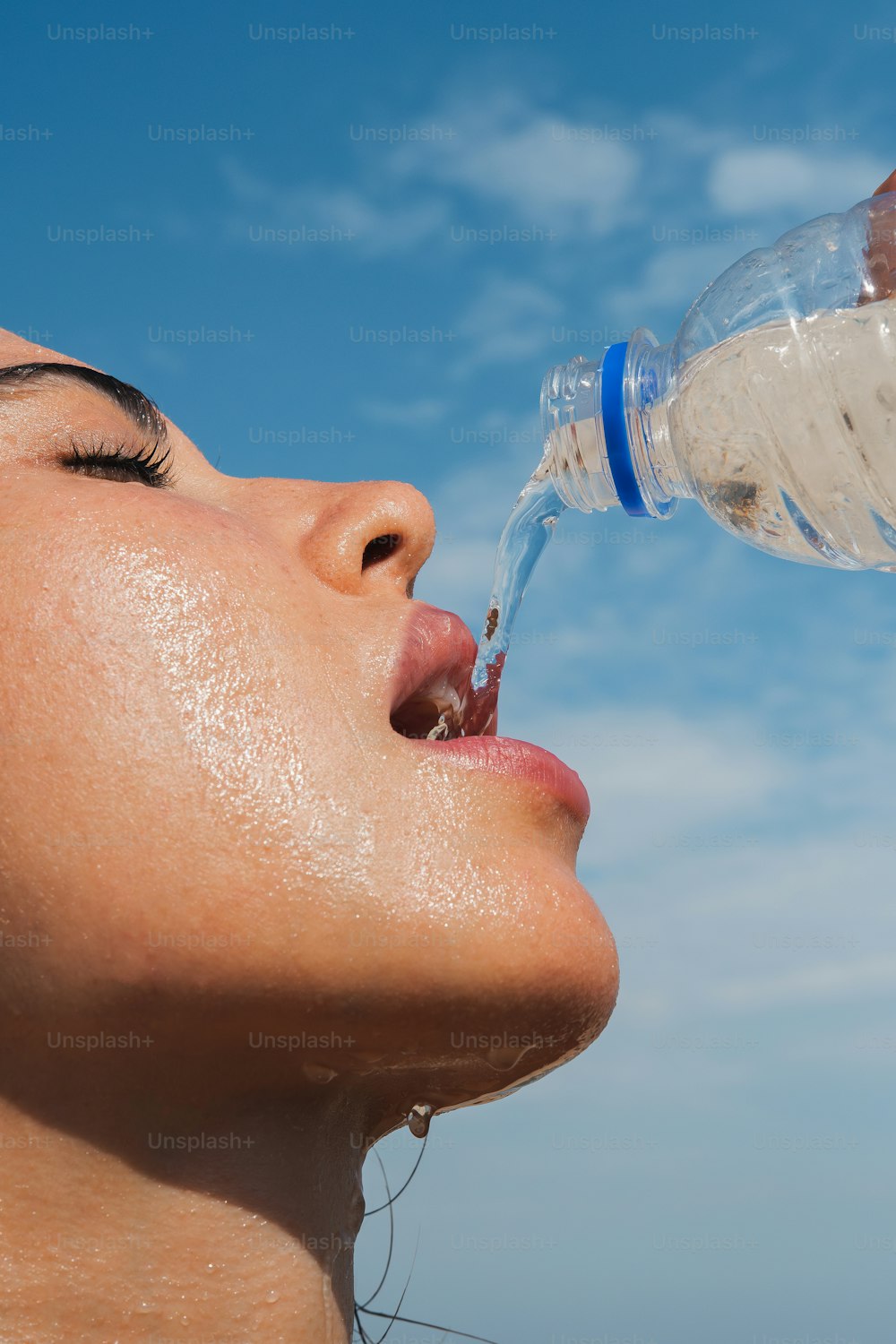 a woman drinking water from a plastic bottle
