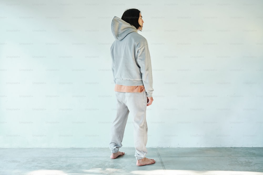 a man in a gray hoodie and white pants