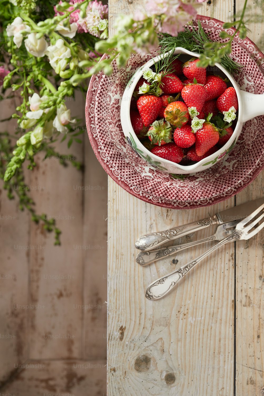 a bowl of strawberries on a red and white plate
