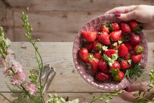 a person holding a bowl full of strawberries