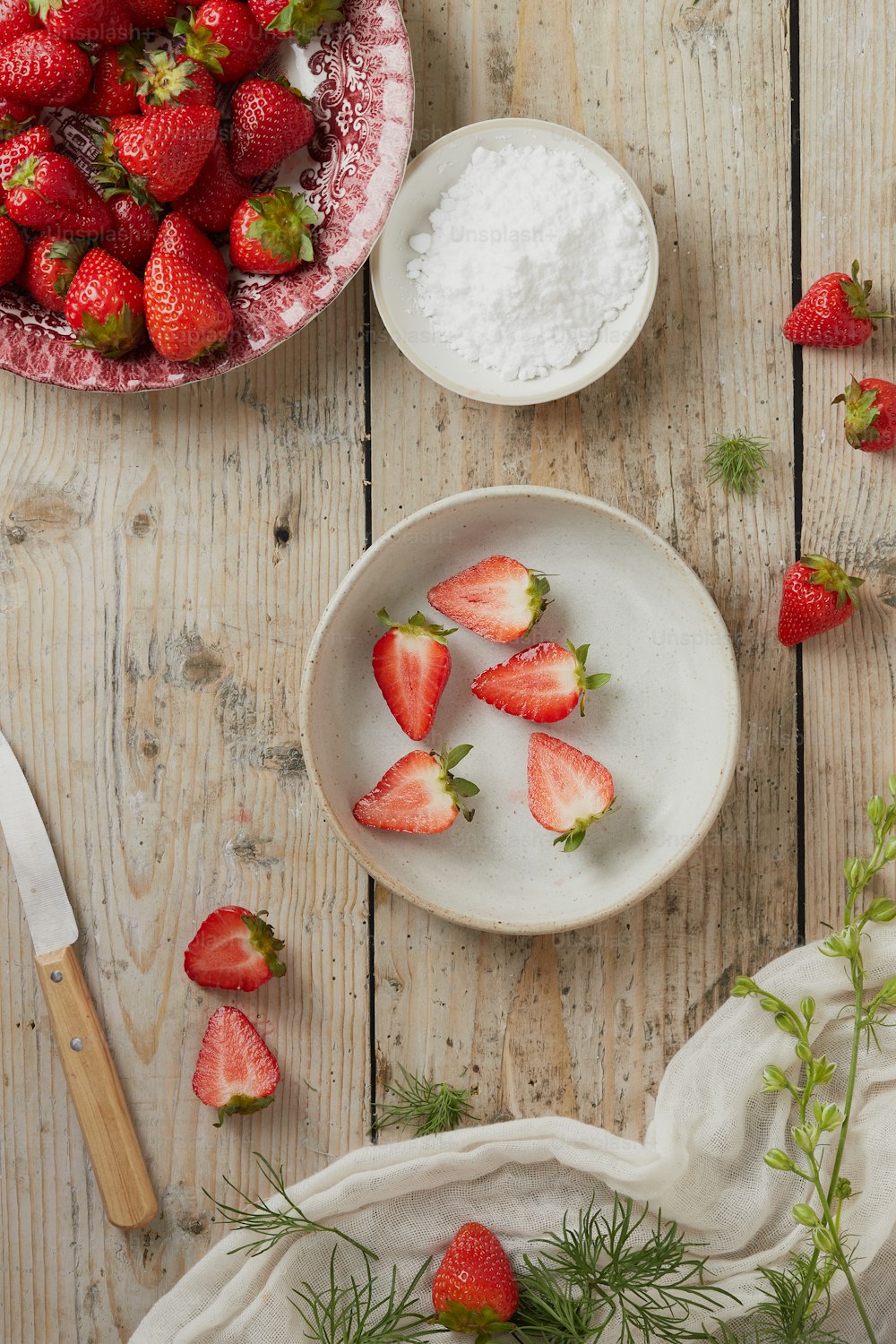 a bowl of strawberries next to a bowl of powder