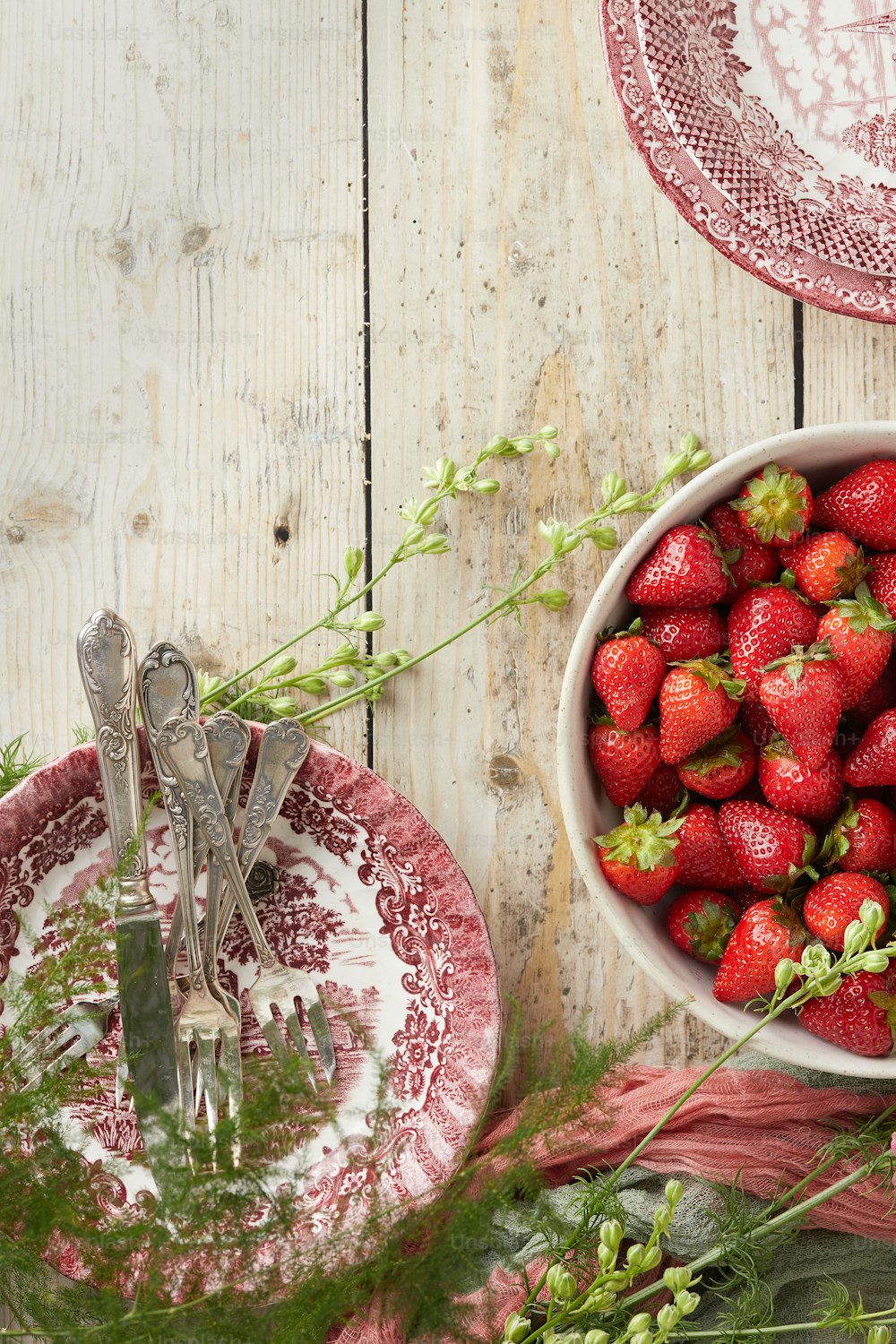 a bowl of strawberries and a plate of greens