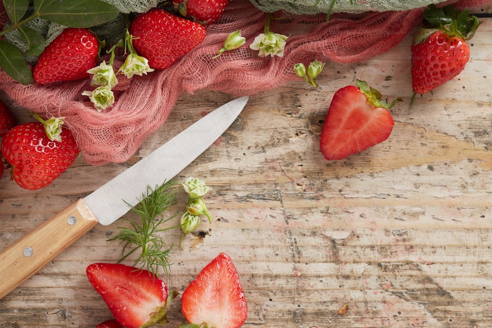 ein Messer und ein paar Erdbeeren auf einem Tisch