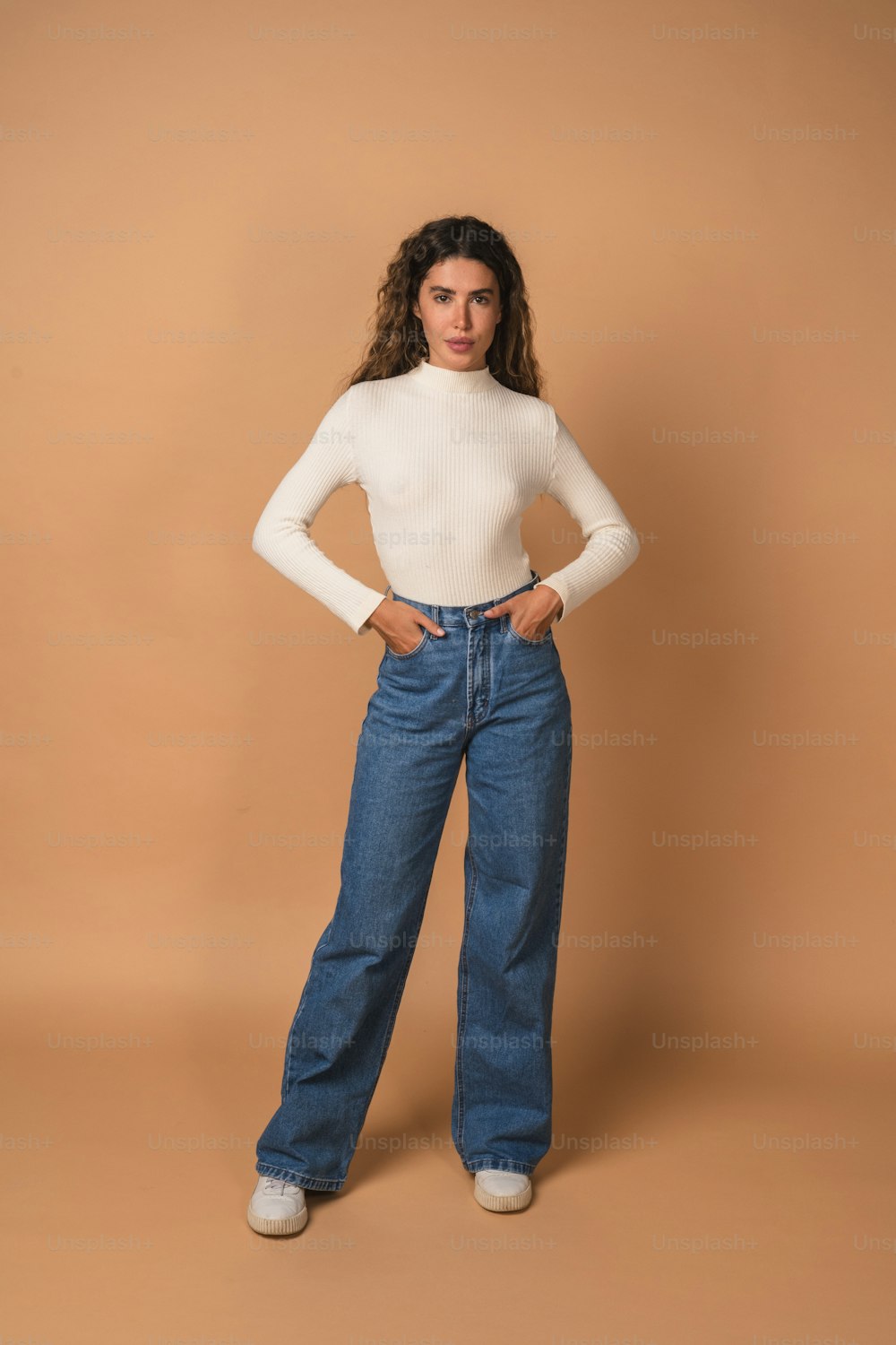 Una mujer con camisa blanca y jeans posando para una foto