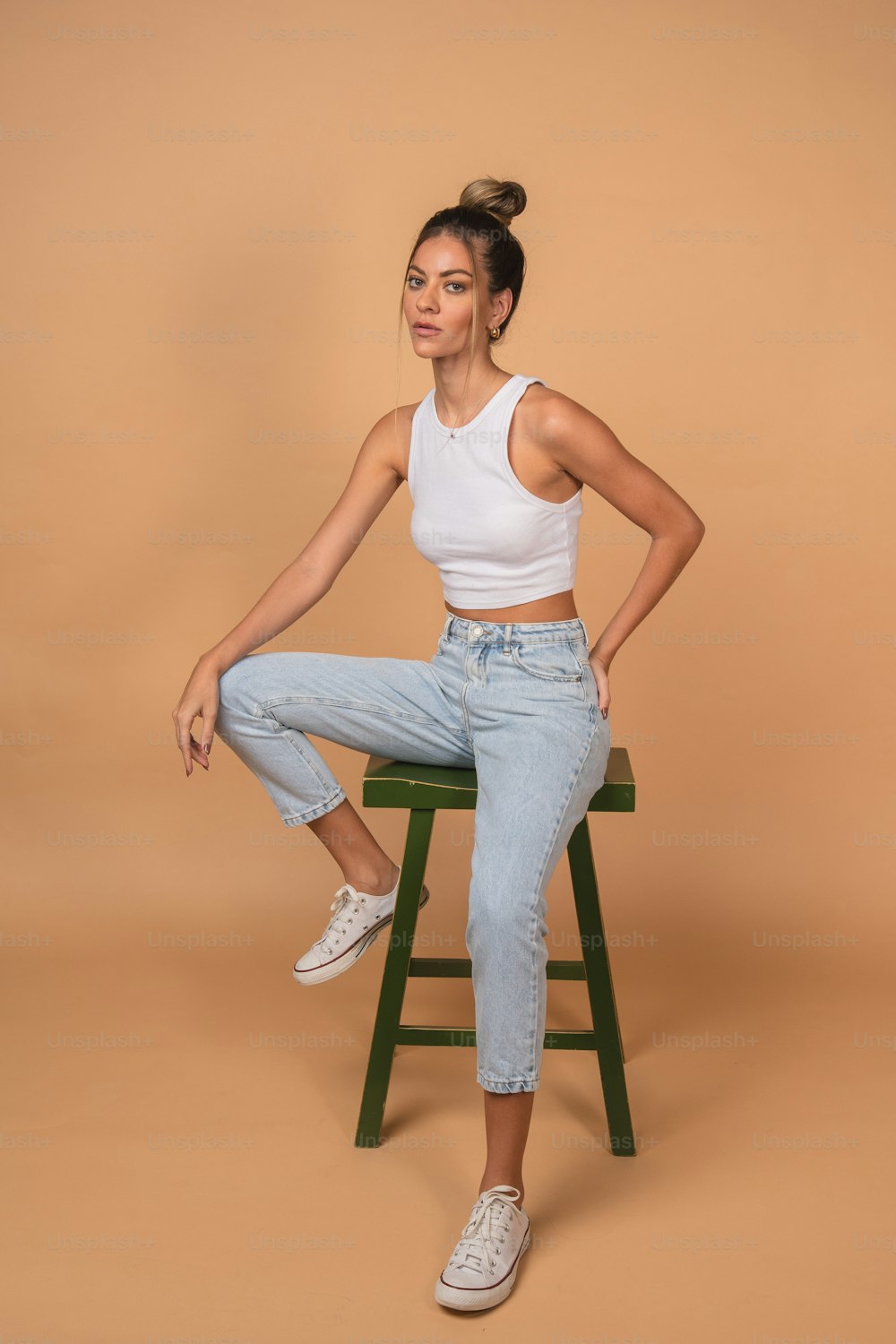 a woman sitting on top of a green stool