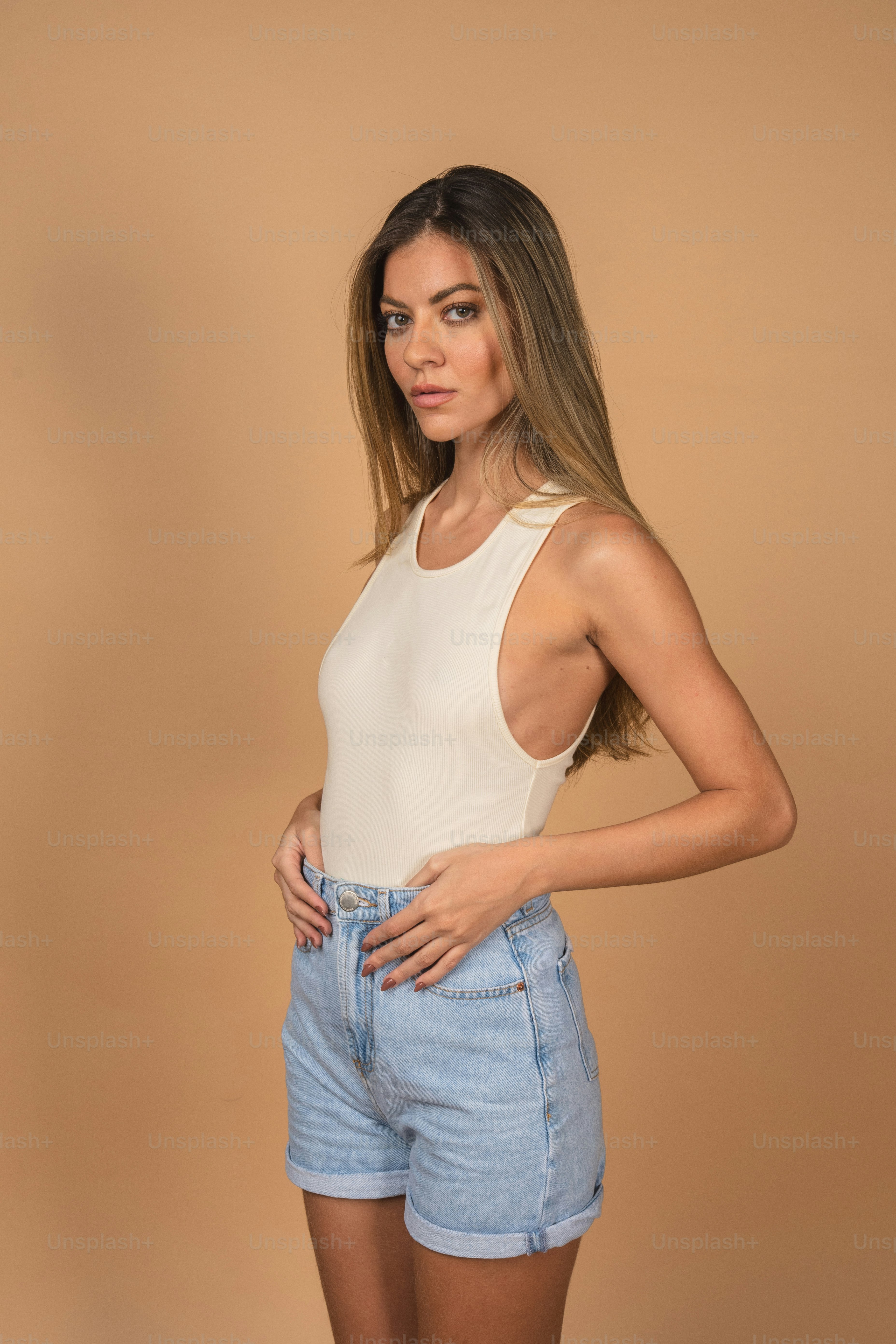 白いタンクトップとデニムのショートパンツを着た女性