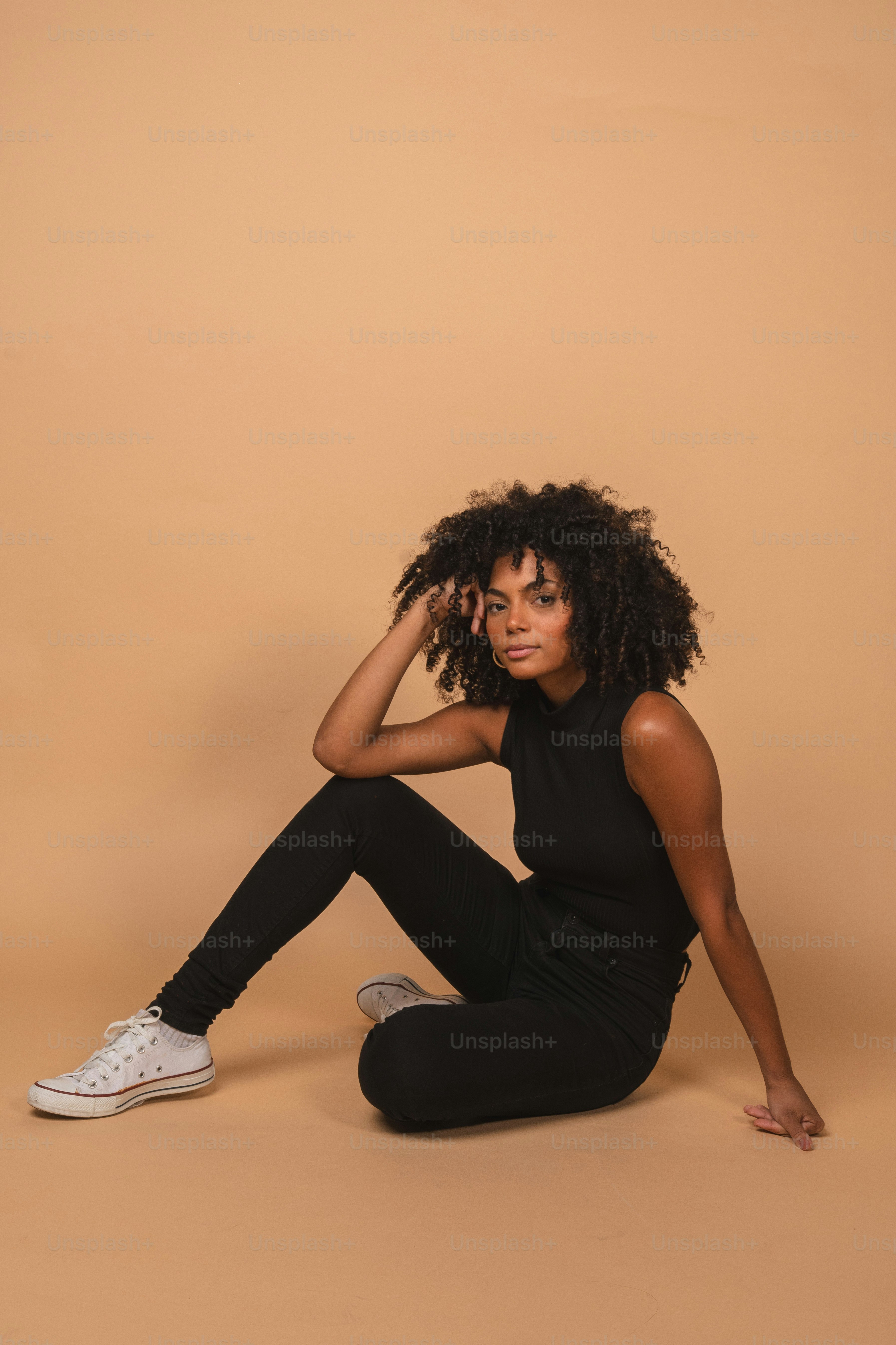 A woman with curly hair wearing a black top photo – Clothing Image on ...