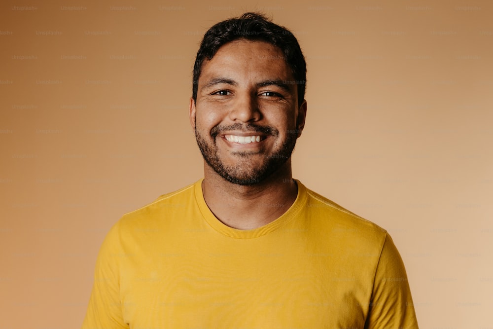 a man in a yellow shirt smiling at the camera