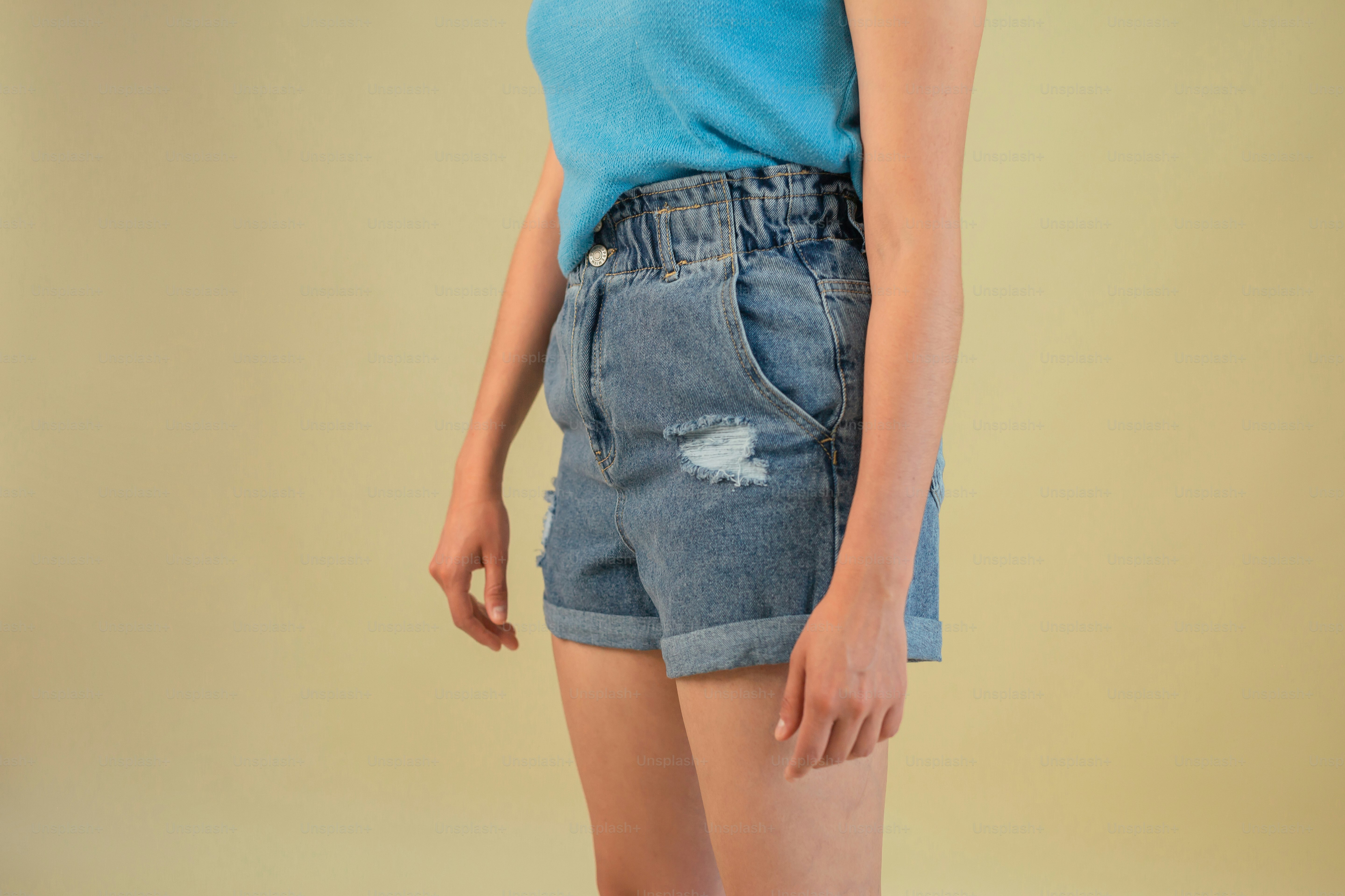 a woman in a blue shirt and jean shorts