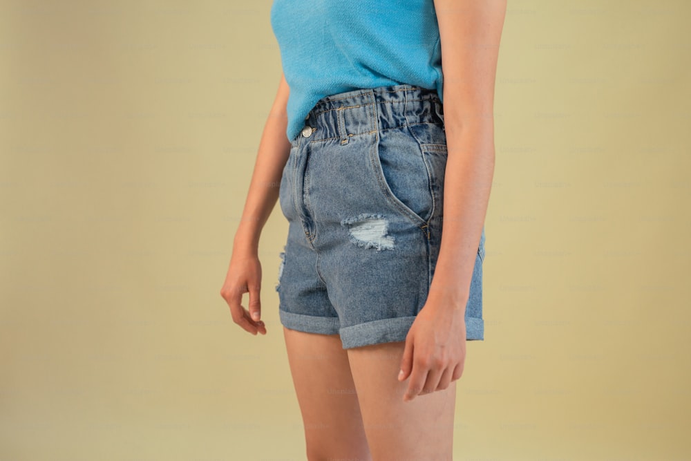a woman in a blue shirt and jean shorts