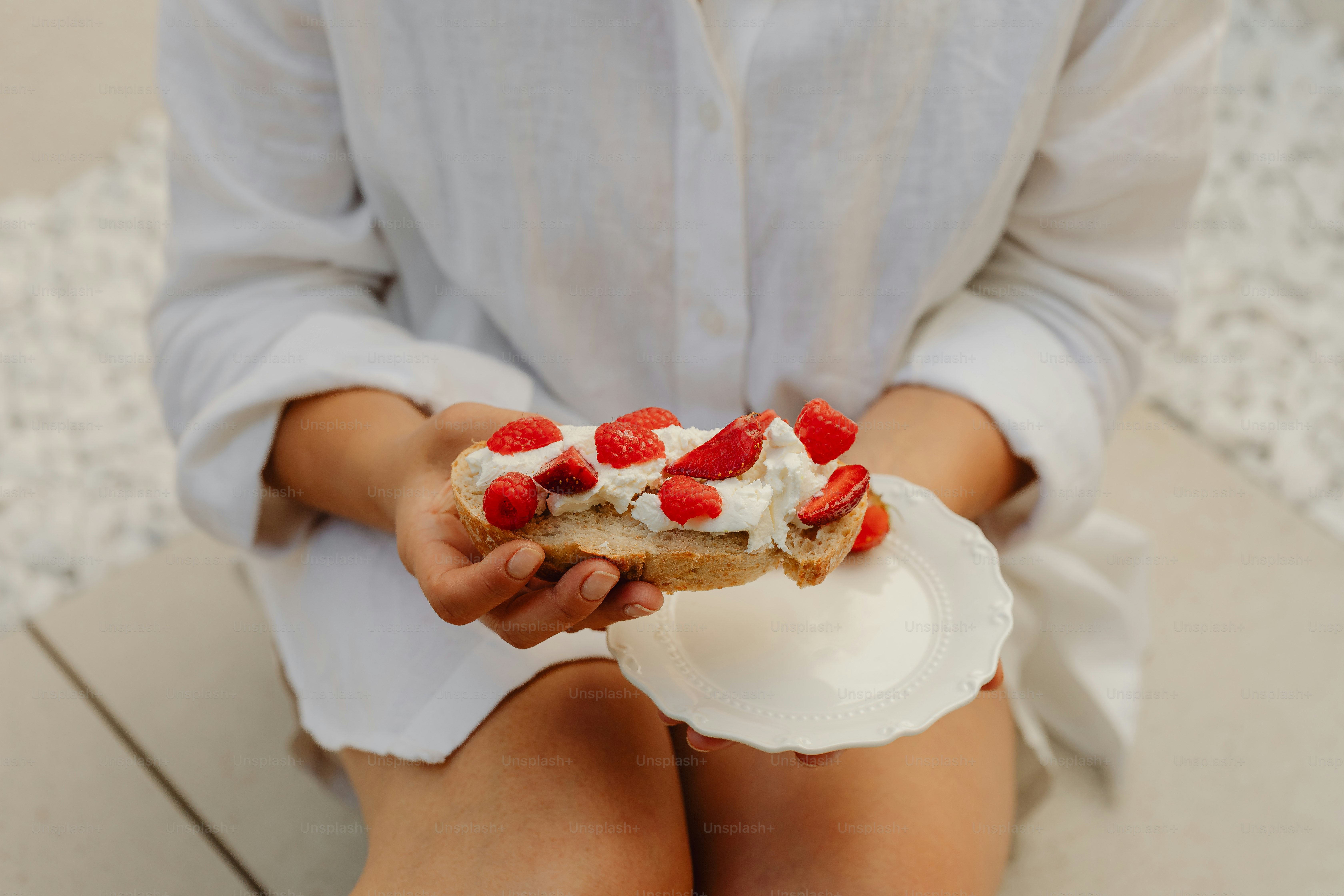 eine Person, die ein Stück Kuchen mit Erdbeeren darauf hält