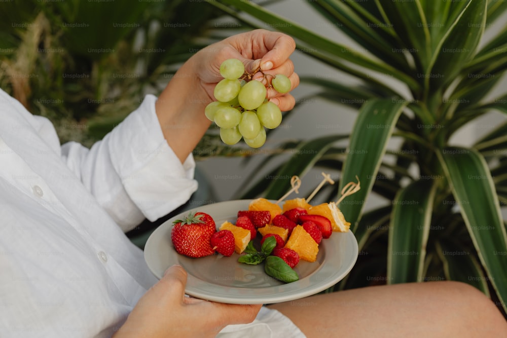a person holding a plate with fruit on it