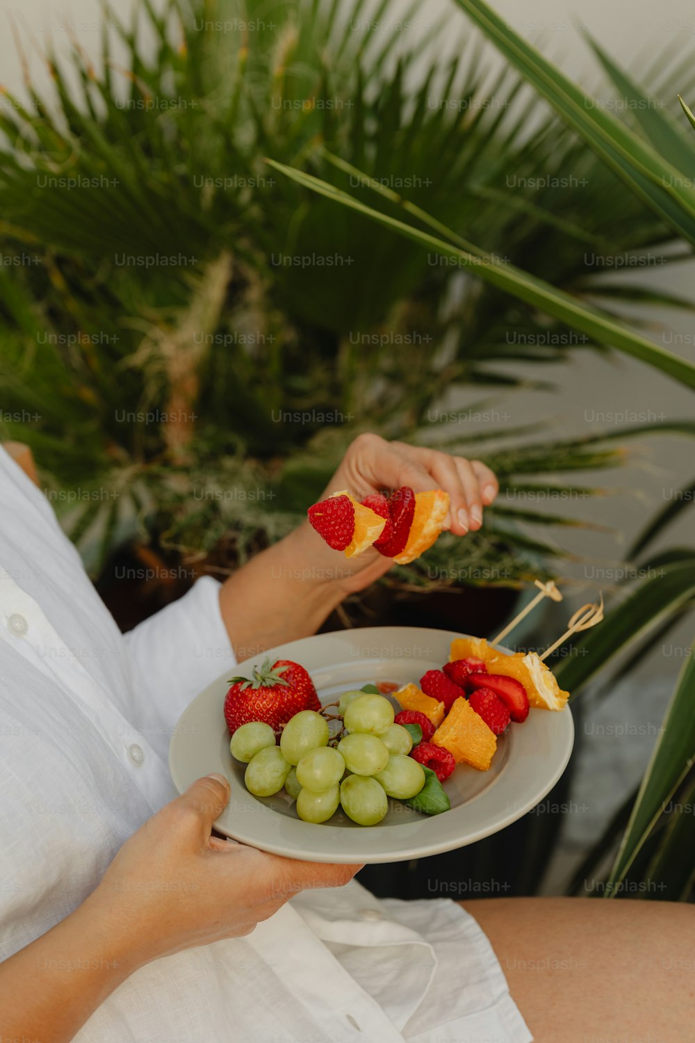 Eine Frau hält einen Teller mit Früchten in der Hand