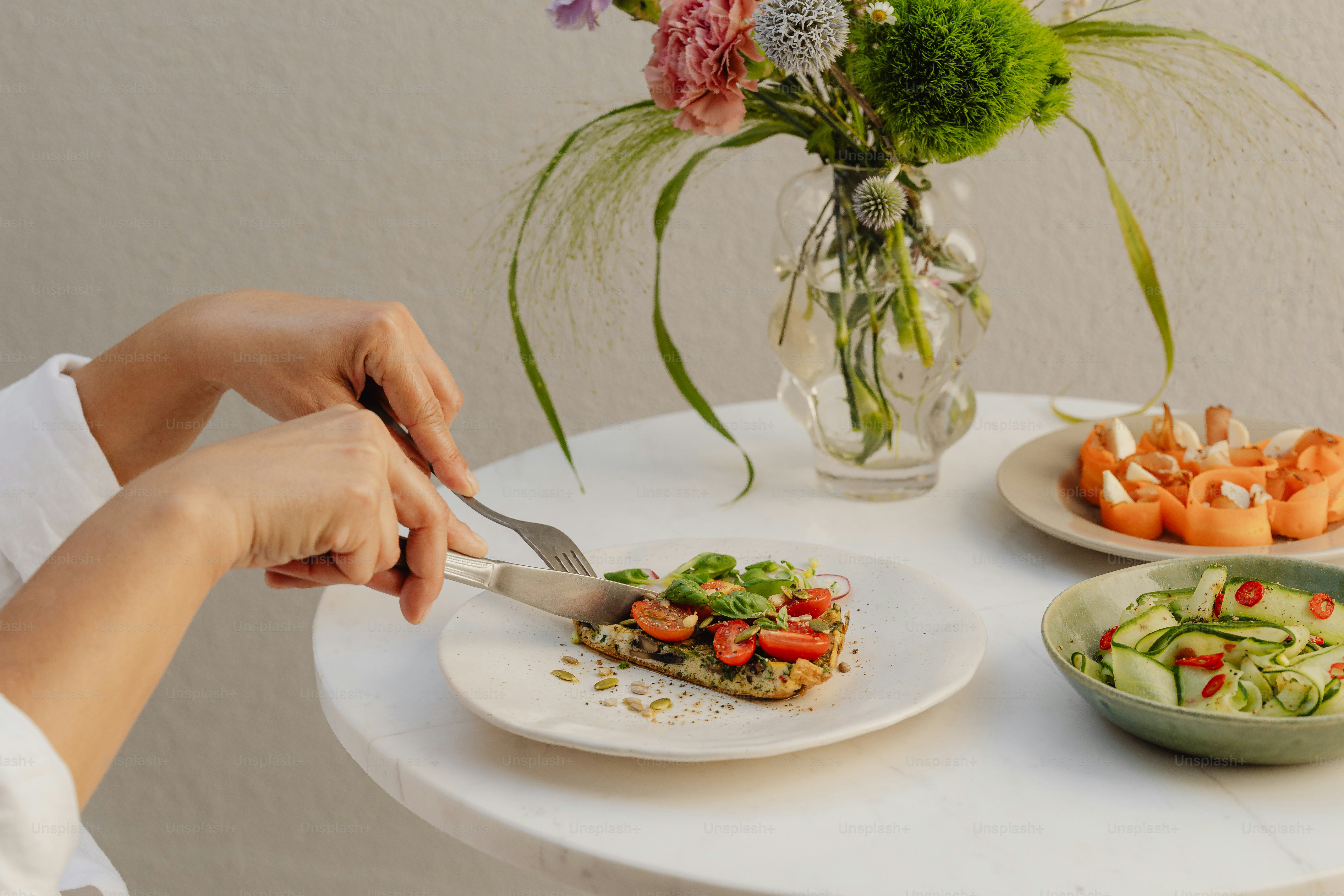 a woman is cutting a sandwich on a table