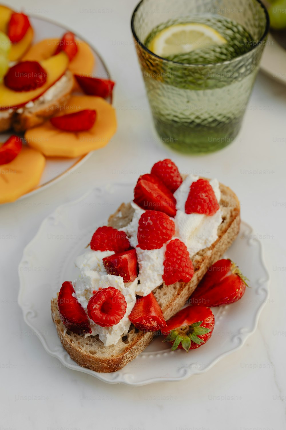 a white plate topped with a piece of bread covered in fruit